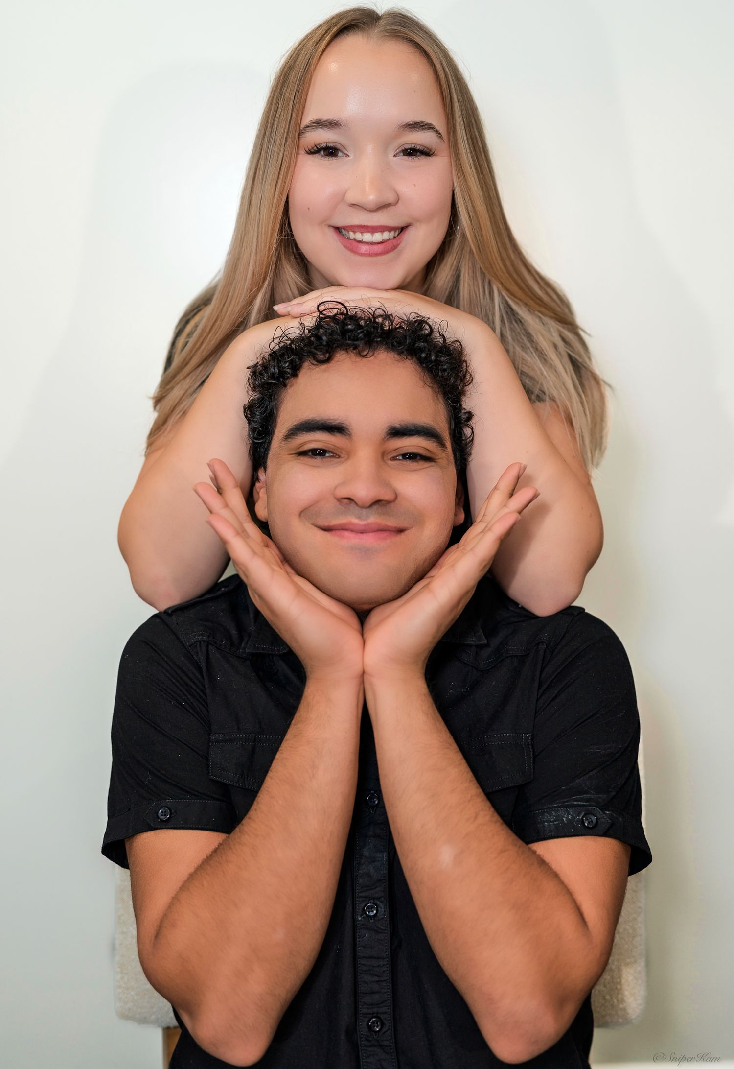 Cheerful couple posing together, woman framing mans smiling face with her hands from above.