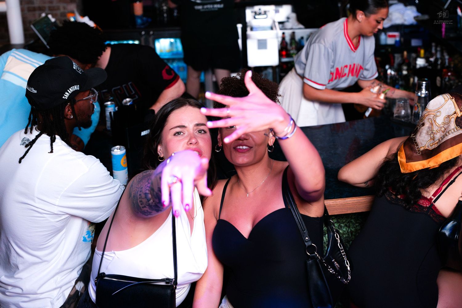 Woman singing into a microphone at a lively nightclub bar event.