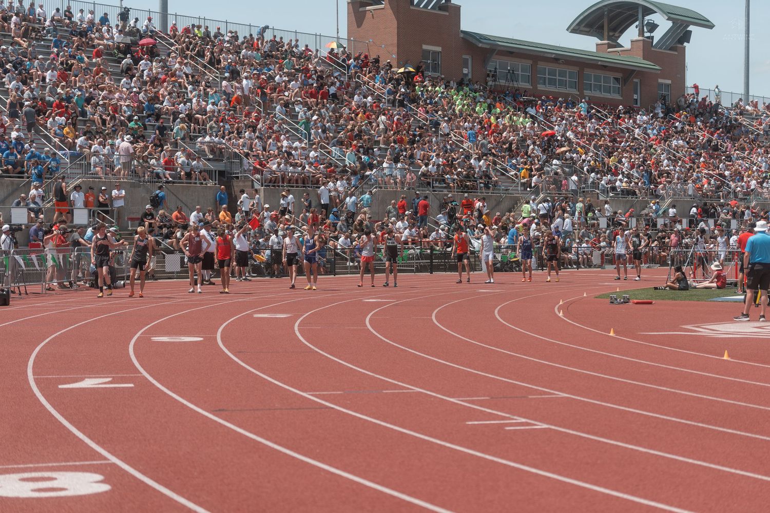 Runners compete in a distance race on a red track before a packed stadium at Ohio State University.