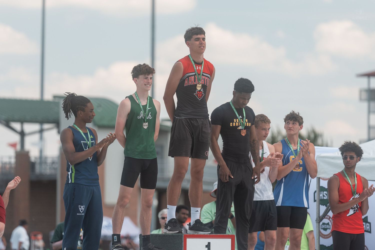 Boys track athletes stand on awards podium at OHSAA state championship competition outdoors.