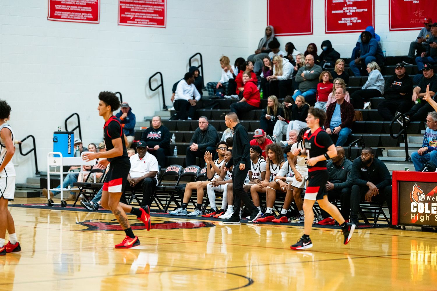 High school basketball players run along the sideline during a game at Cole High School gymnasium.