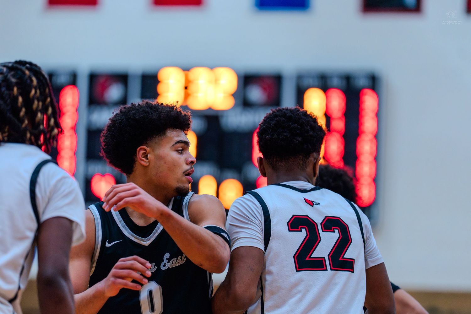 Lakota East #0 interacts with opponent #22 near the scoreboard during a basketball game.