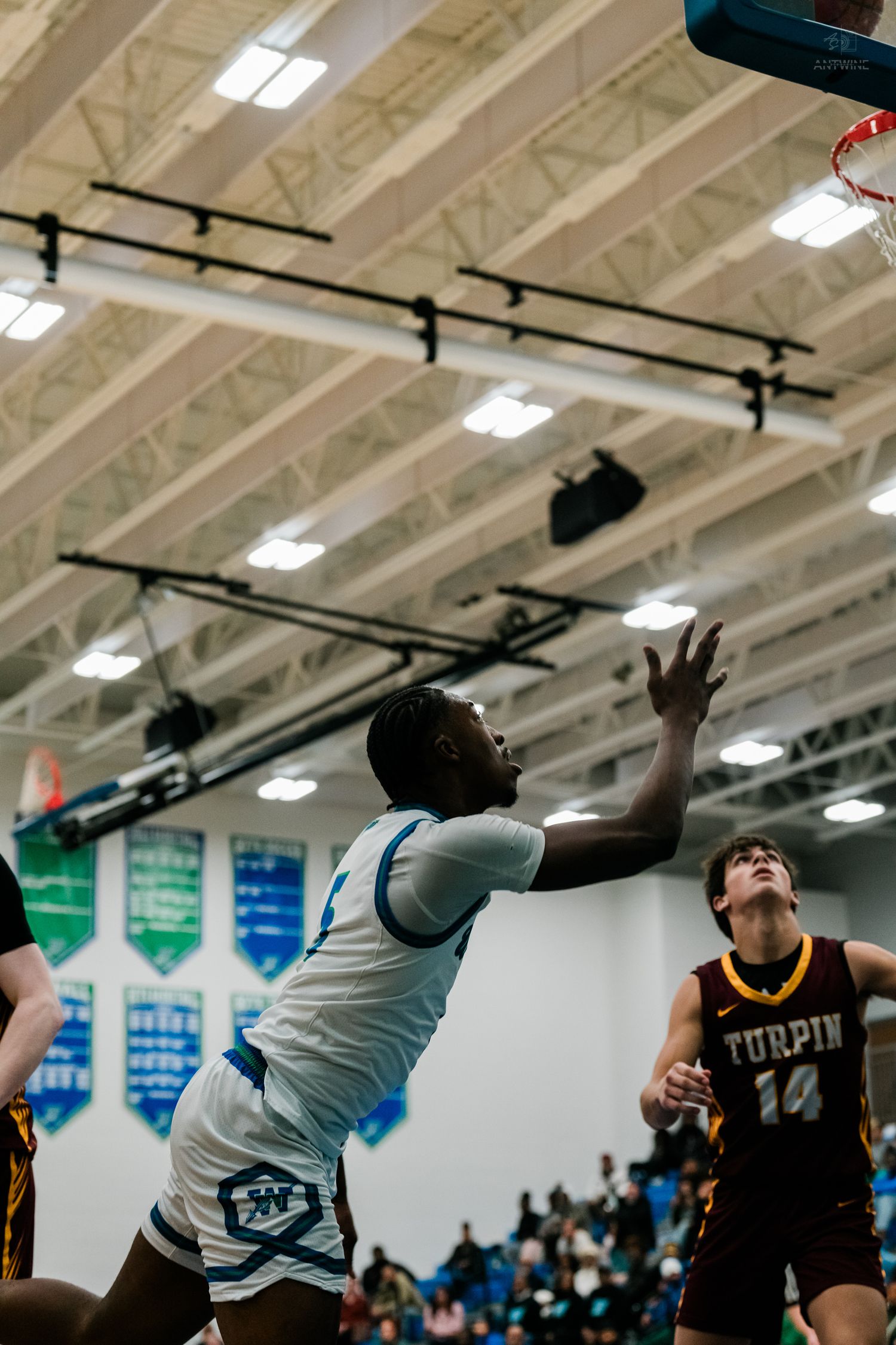 A Winton Woods player leaps toward the basket for a layup against a Turpin defender in a high school game.