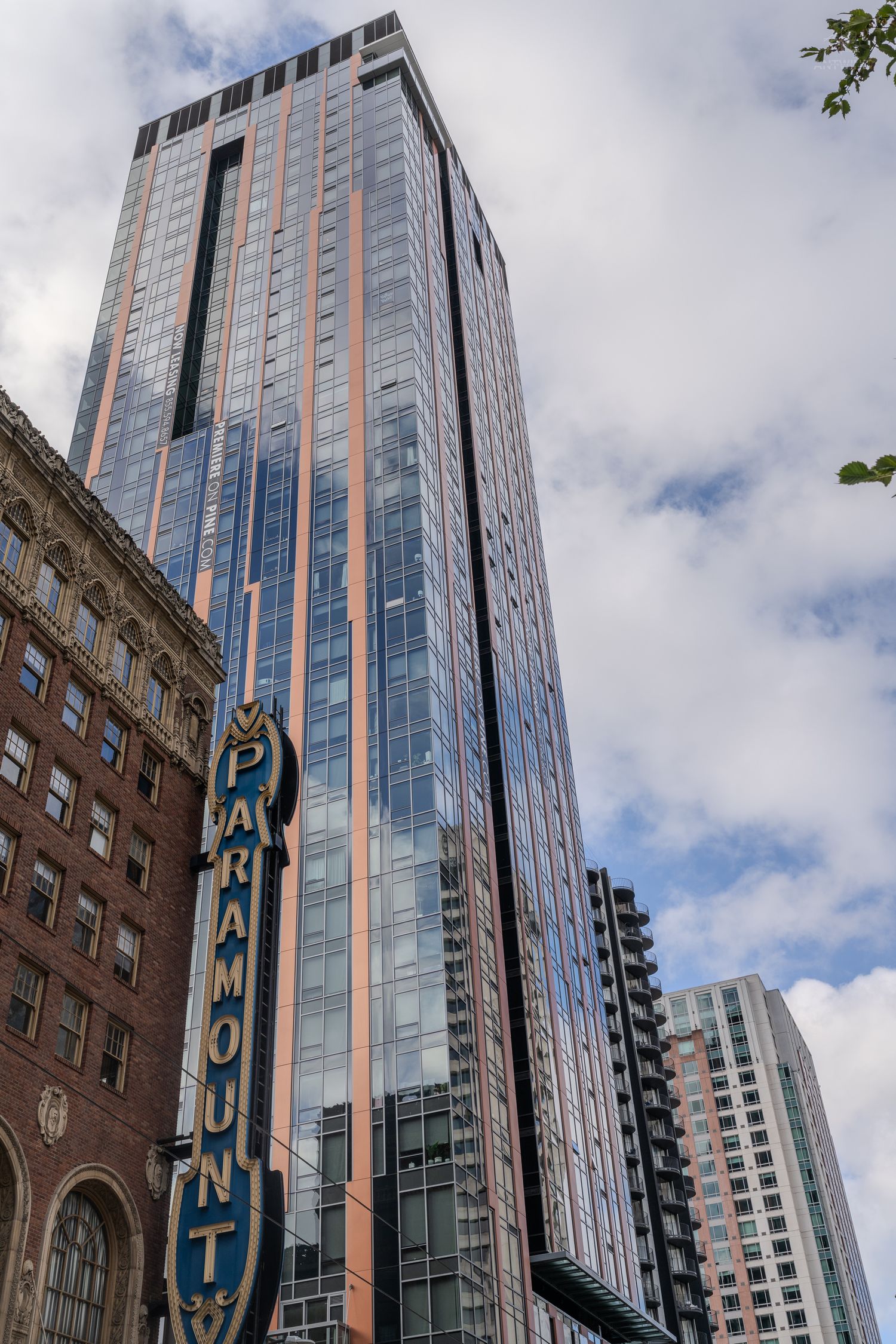 Paramount Theatre sign beside a tall modern glass skyscraper with copper accents in downtown Seattle.