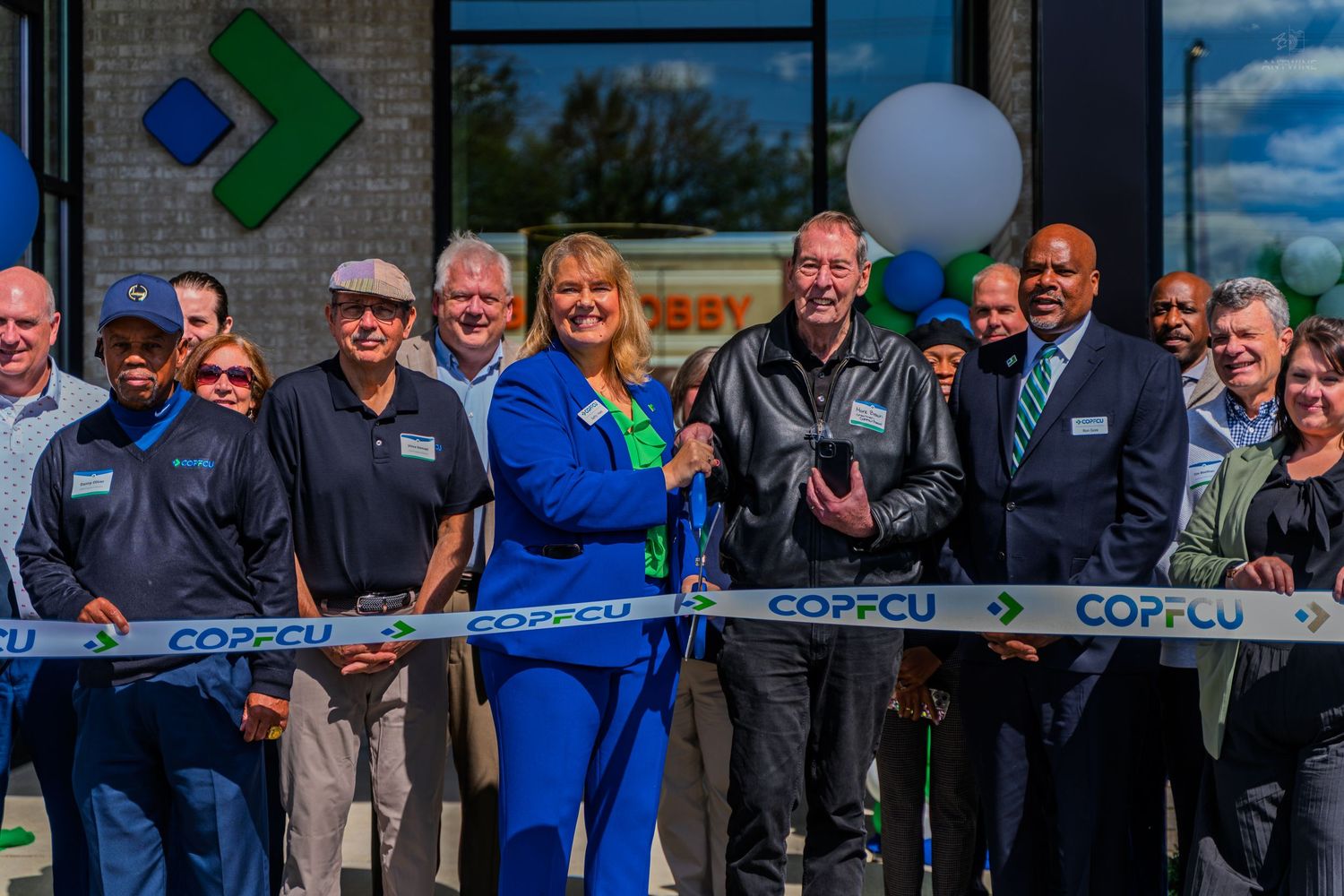 COPFCU credit union ribbon cutting ceremony with smiling staff and officials outside a modern branch location.
