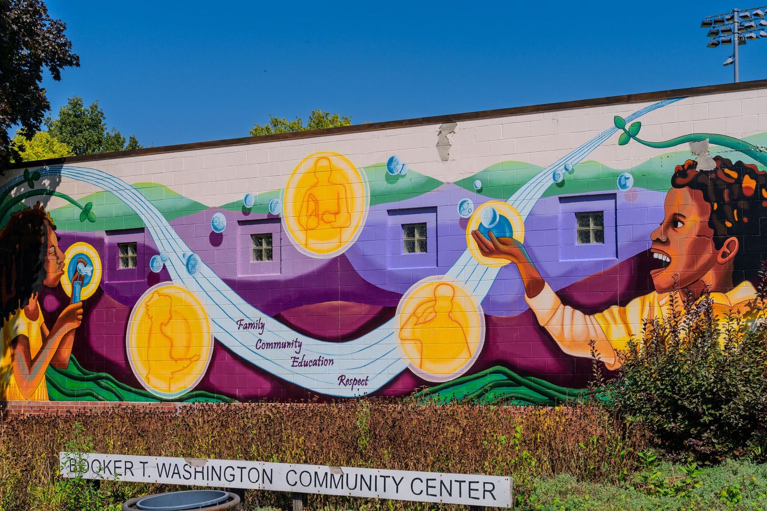 Colorful mural at Booker T. Washington Community Center featuring coins, figures, and vibrant community-themed artwork.