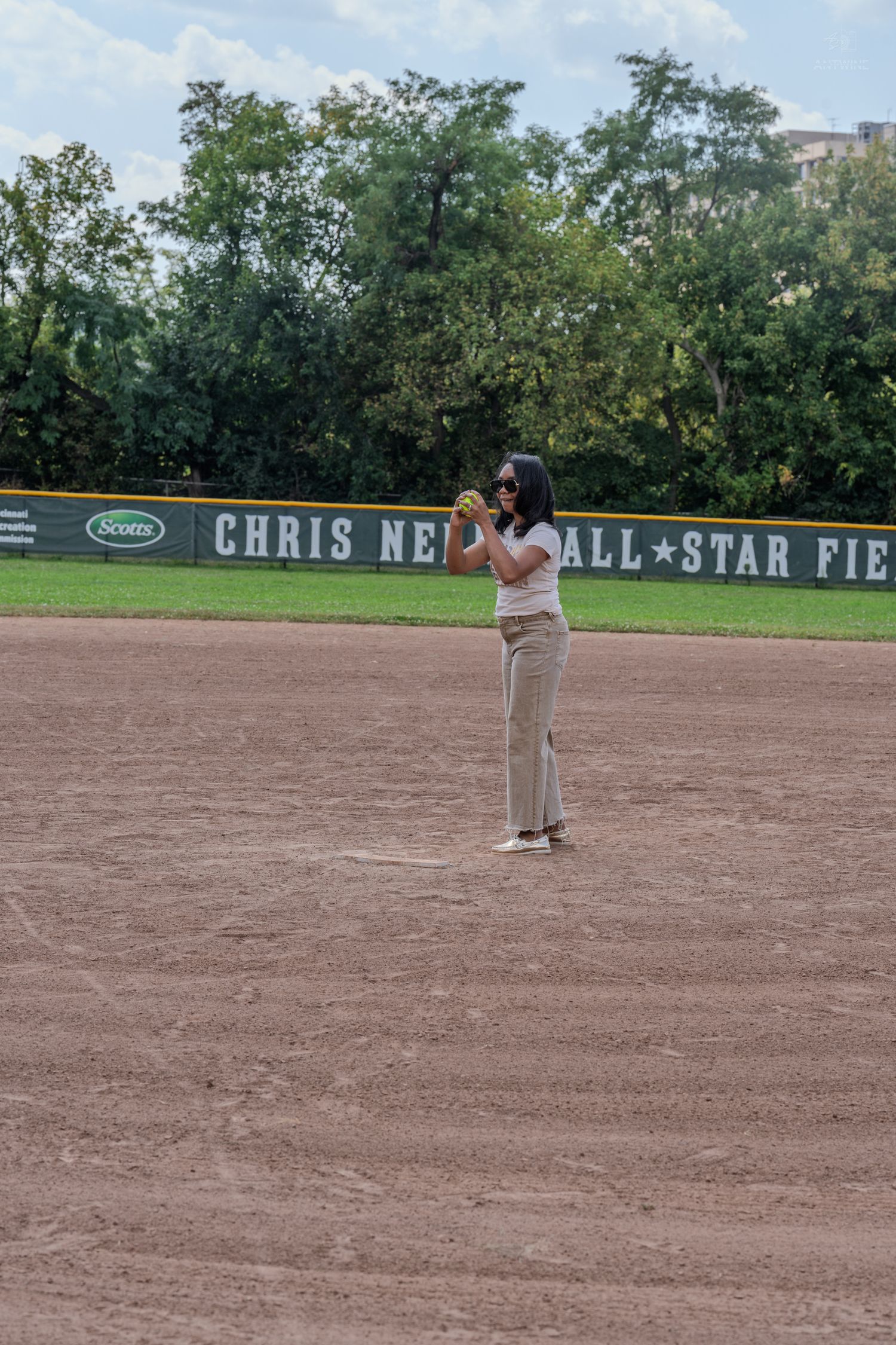 Woman standing alone on a softball field at Chris Newell All-Star Field preparing to throw a pitch.