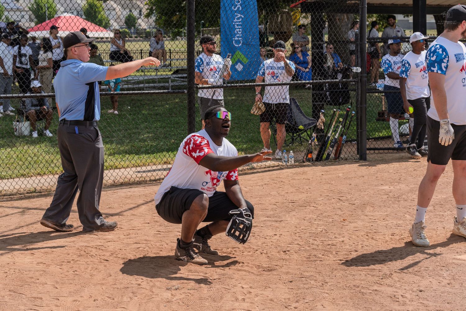 Baseball catcher crouching at home plate during an outdoor game with umpire nearby.