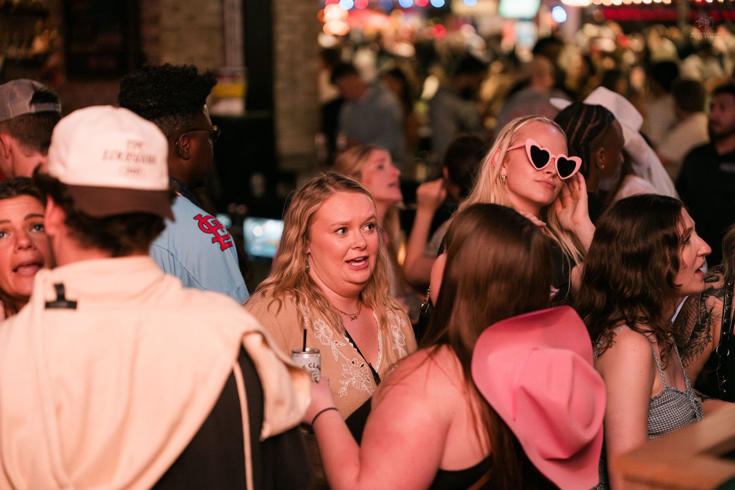 Group of young people socializing outdoors at a busy nighttime street festival or bar event.