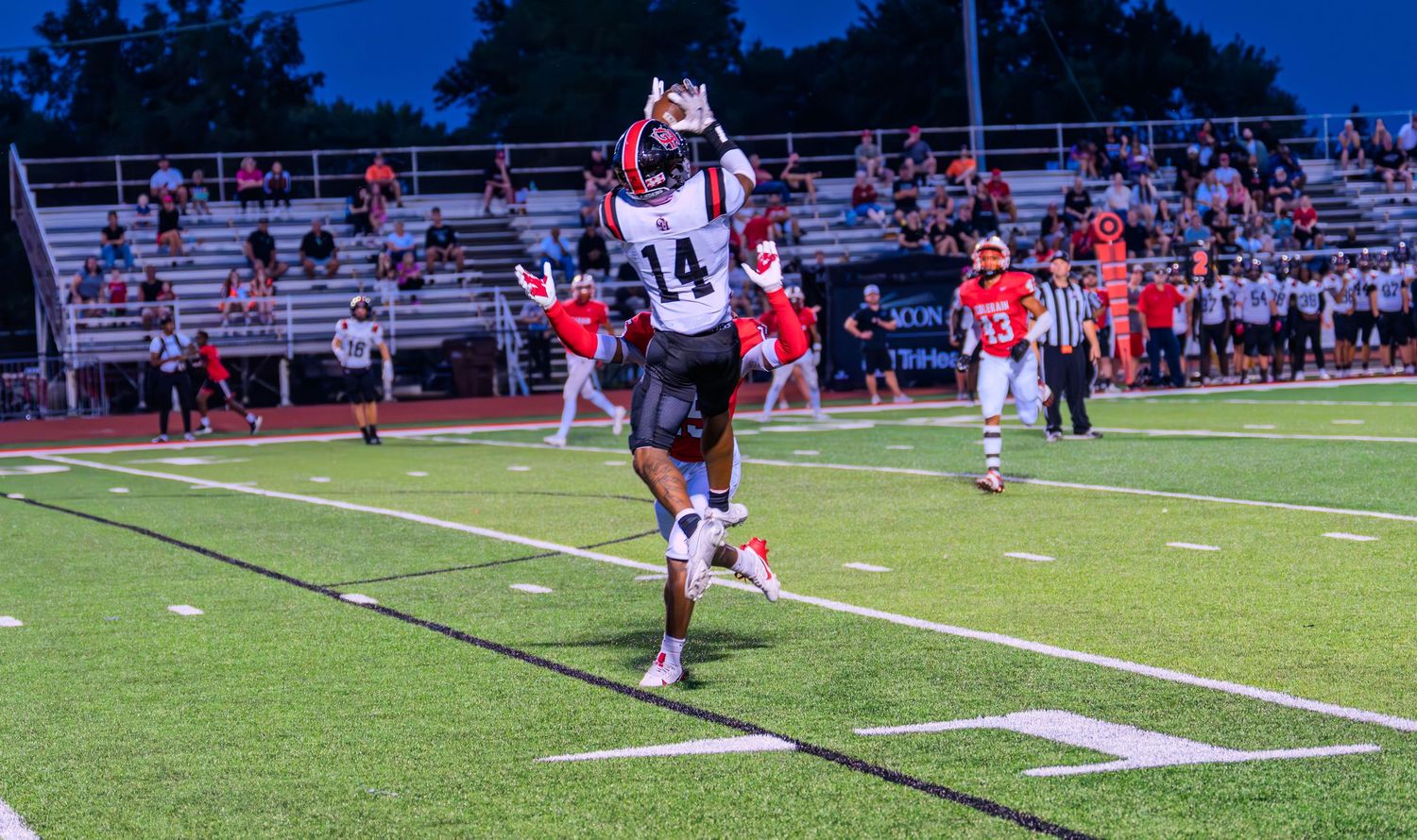 Colerain football player number 14 leaps to make a catch during a night game.