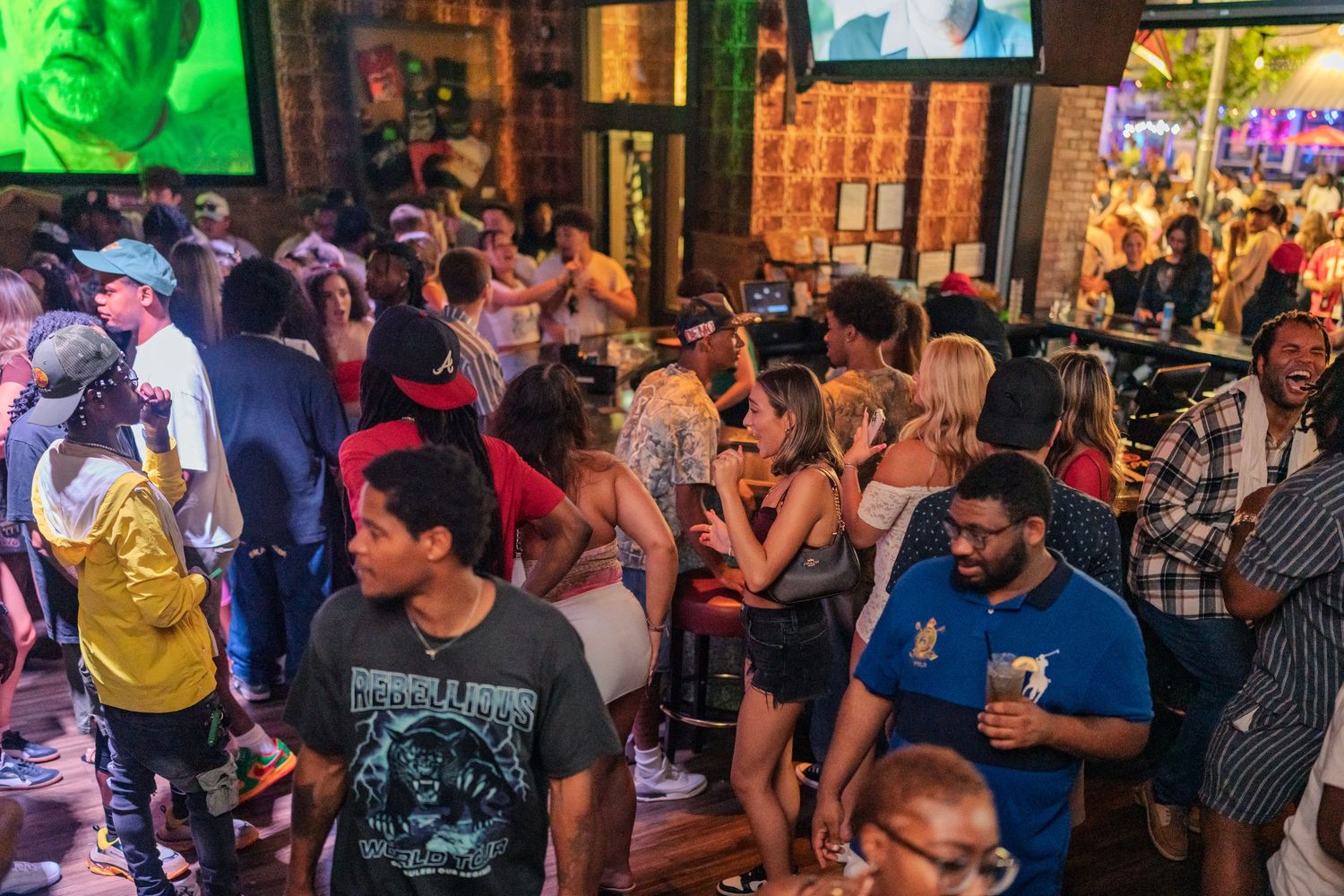 Busy bar venue filled with diverse crowd of people socializing with drinks during a lively night event.