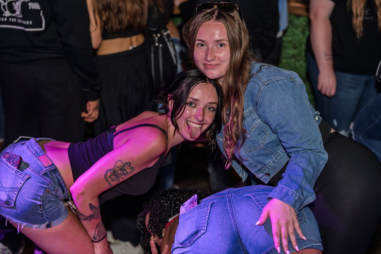 Two young women posing and smiling together at an outdoor nighttime party event.
