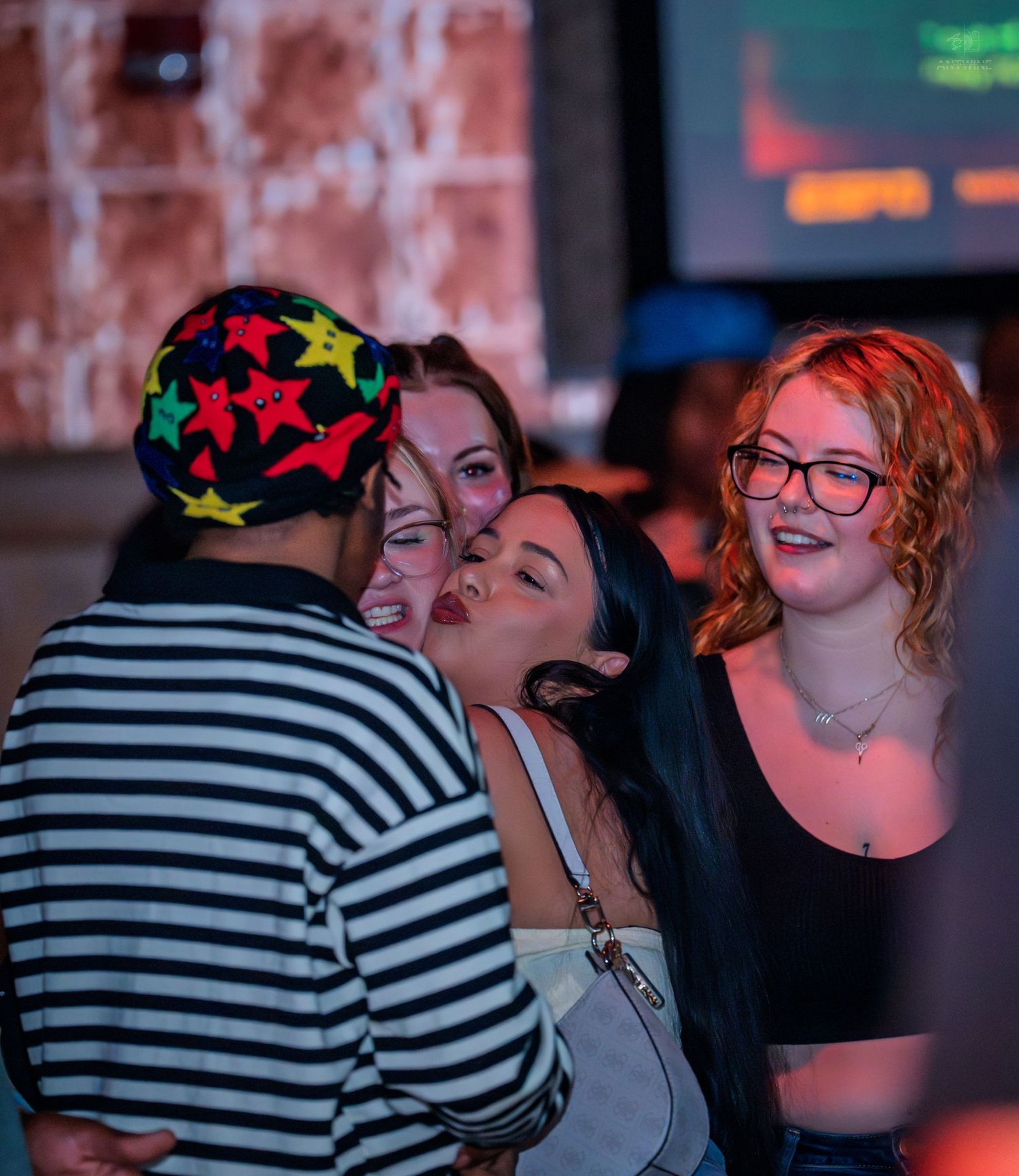Group of young women laughing and taking photos together at a nightclub party.