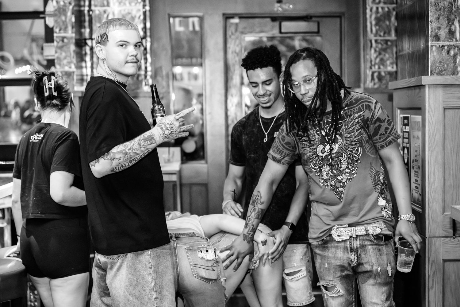 Three men laughing and socializing together in a casual bar setting in black and white.