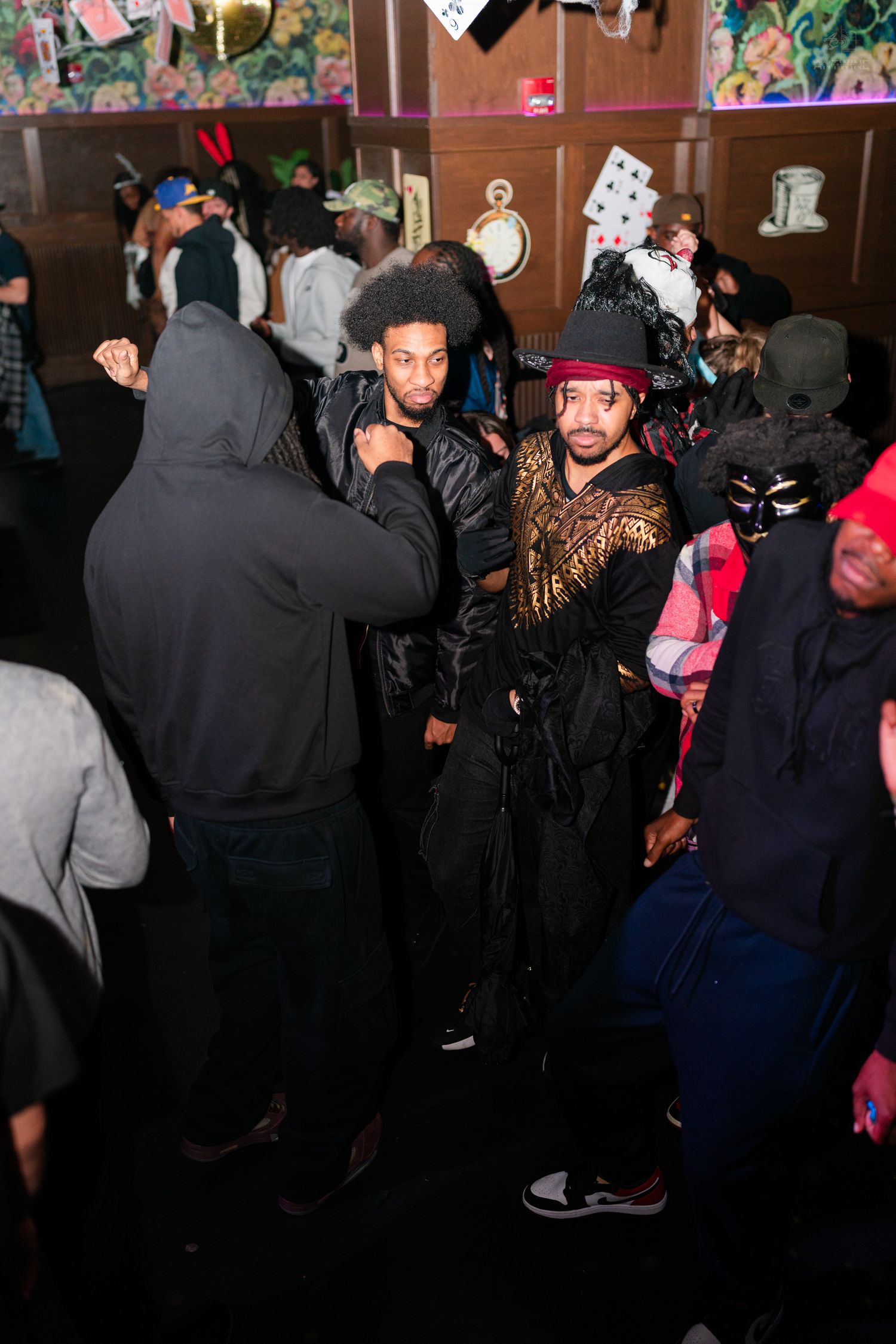 Man in elaborate pirate costume socializing at a crowded Halloween bar party.