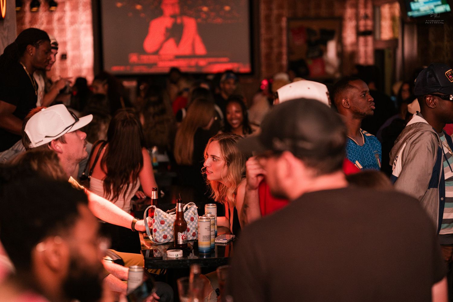 Diverse crowd enjoying drinks and socializing at a lively indoor bar event.