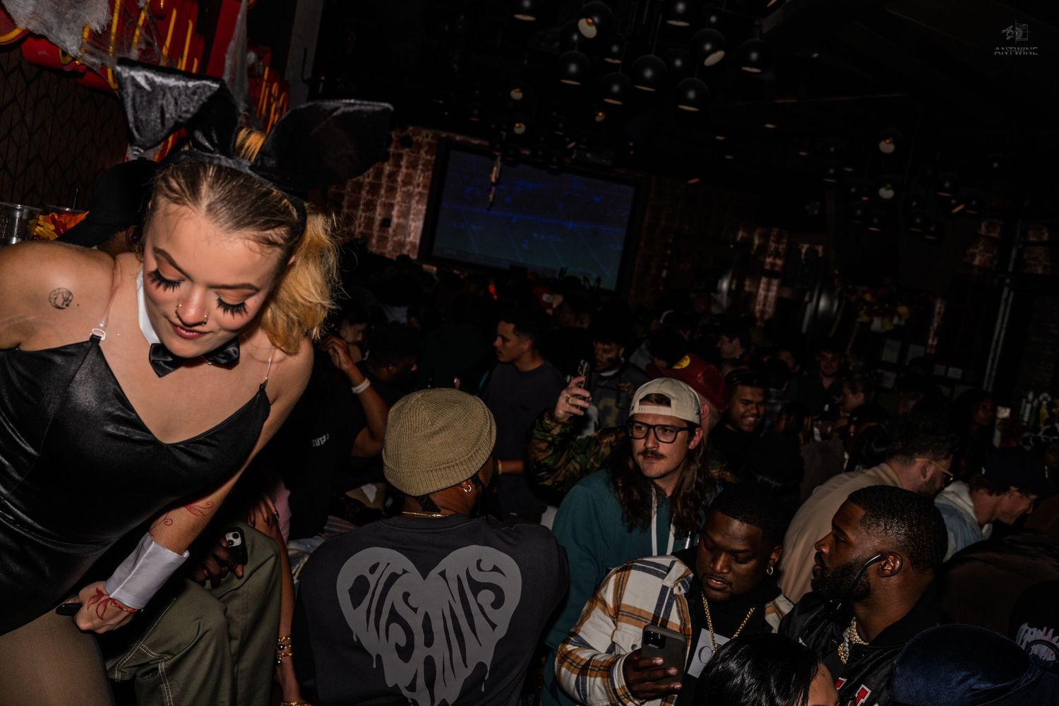 Woman in bunny costume mingles with crowd at a packed nightclub event.