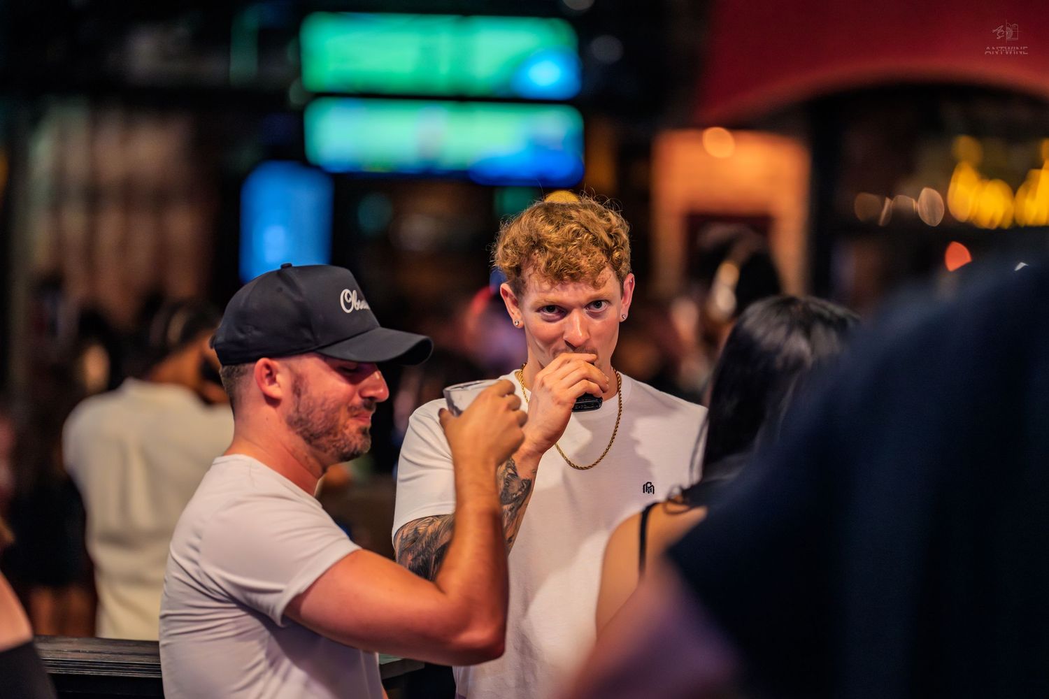 Two men in baseball caps having a conversation at a nighttime outdoor venue.