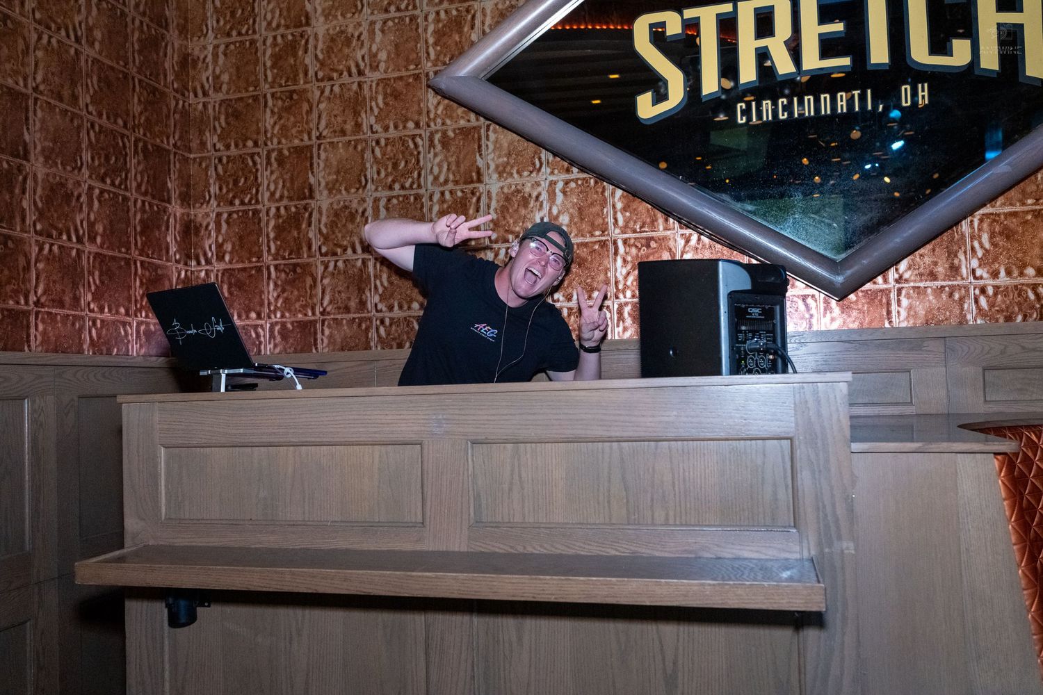 DJ performing at Stretch Cincinnati OH bar venue behind wooden booth with equipment.