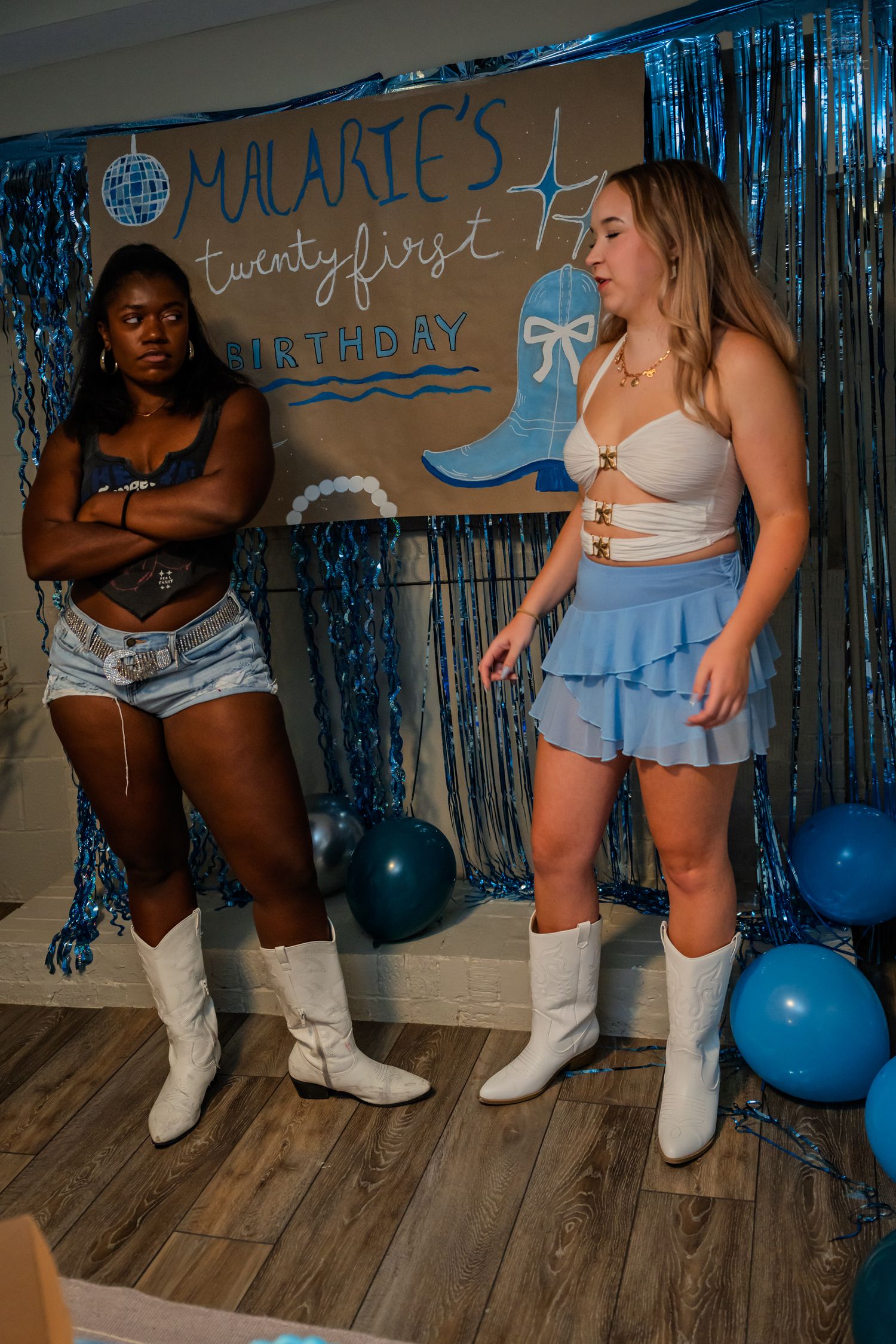 Two women in white cowboy boots interact at Malarie's 21st birthday party celebration.
