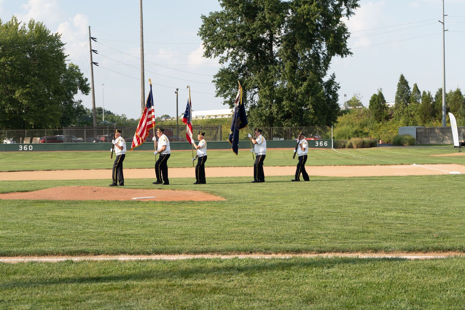 Color guard ceremony on a baseball field with flag bearers standing on the pitcher's mound during a pre-game event.