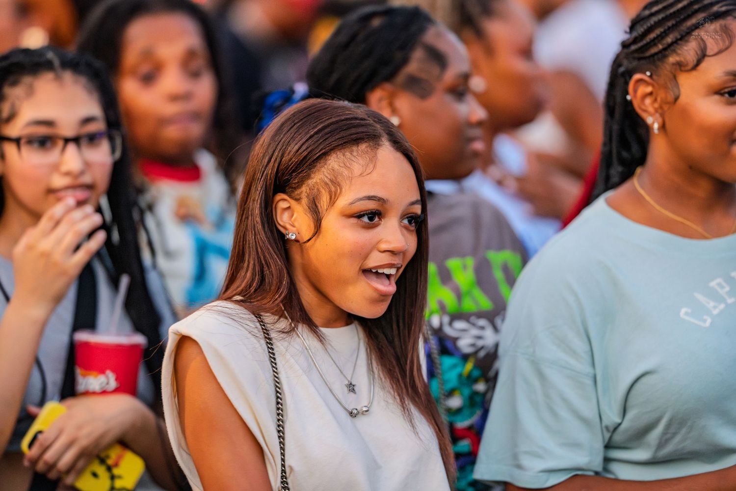 Young woman smiling in crowd at outdoor Juneteenth celebration event holding red cup.