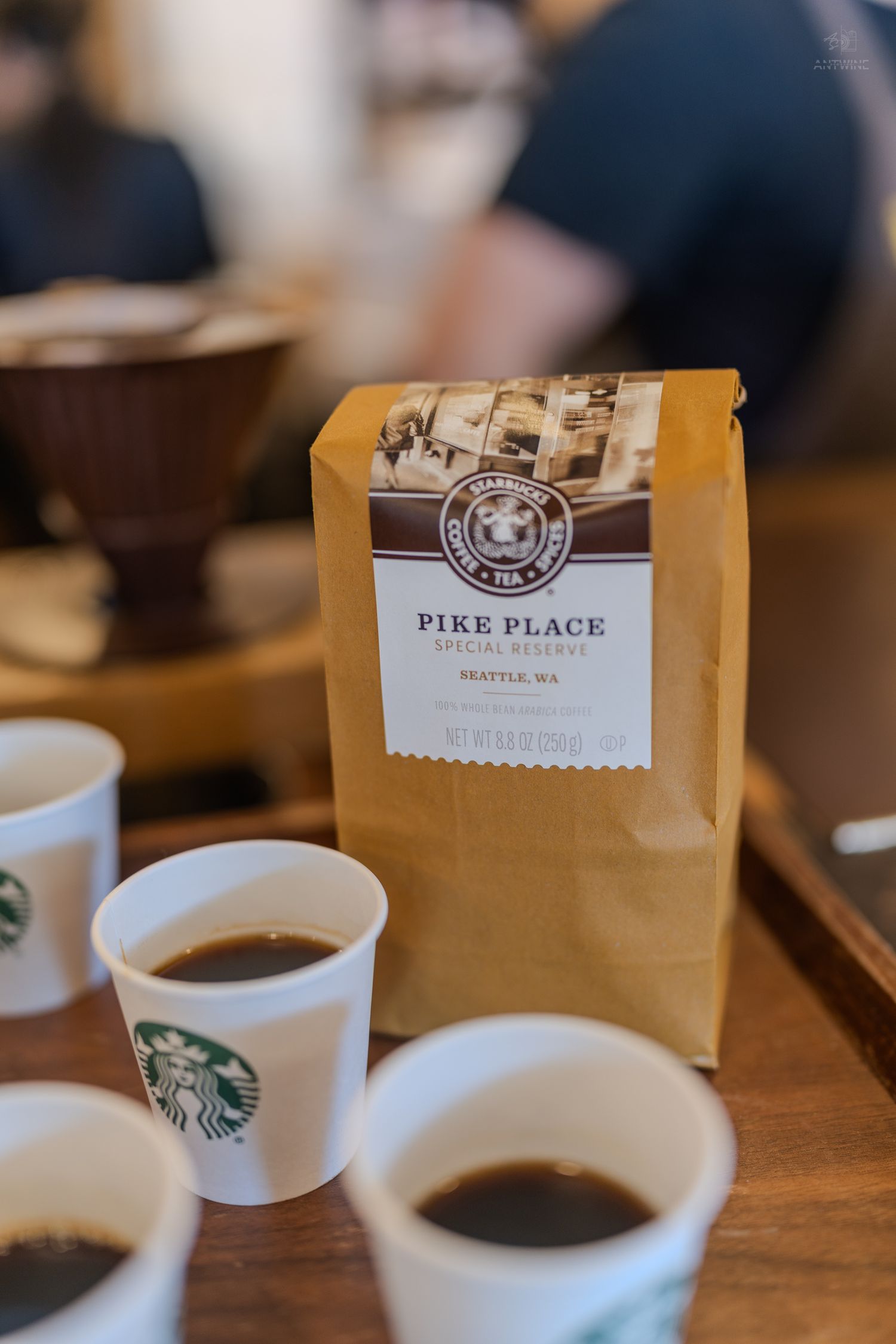 Starbucks Pike Place Special Reserve coffee bag with sample cups on a wooden table.