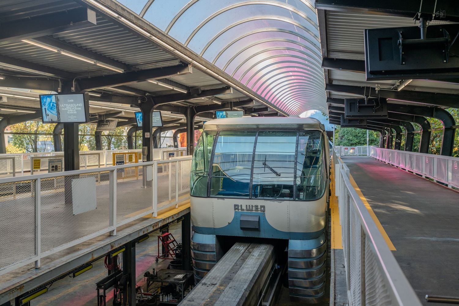 Seattle monorail train arriving at station platform under modern curved roof architecture.