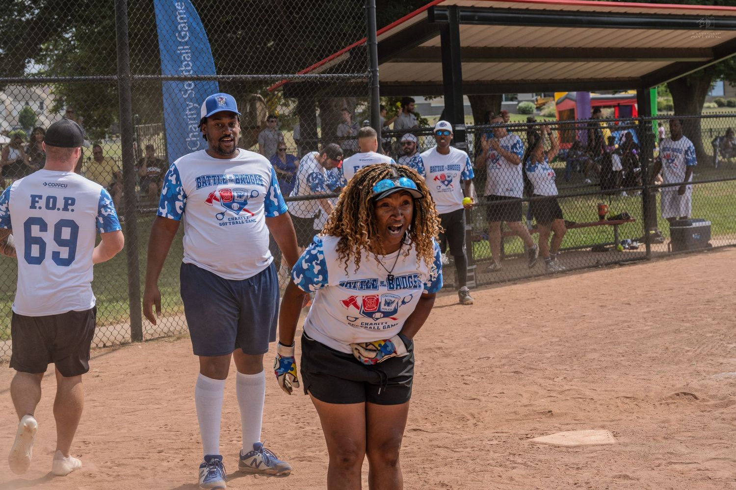 Smiling softball players in blue uniforms walking along the baseline during a recreational game.