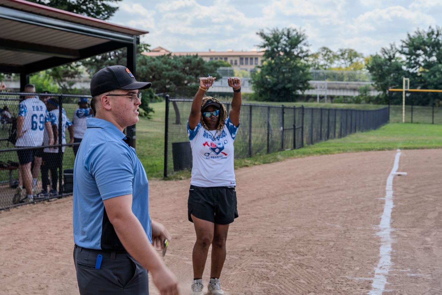 Woman celebrating on softball field with fist raised wearing white jersey.