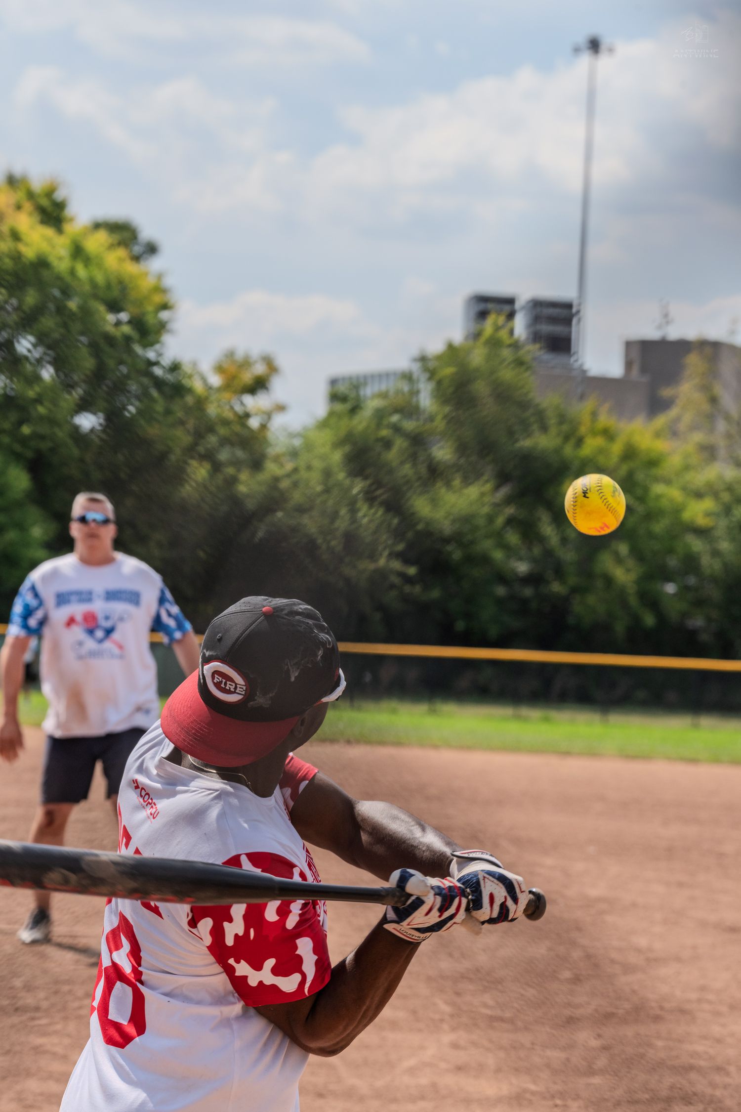 A batter swings at a yellow softball during a Battle of the Badges charity softball game.