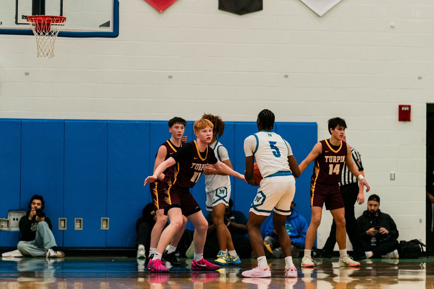 Turpin players set screen for teammate against Winton Woods player #5 during high school basketball game.