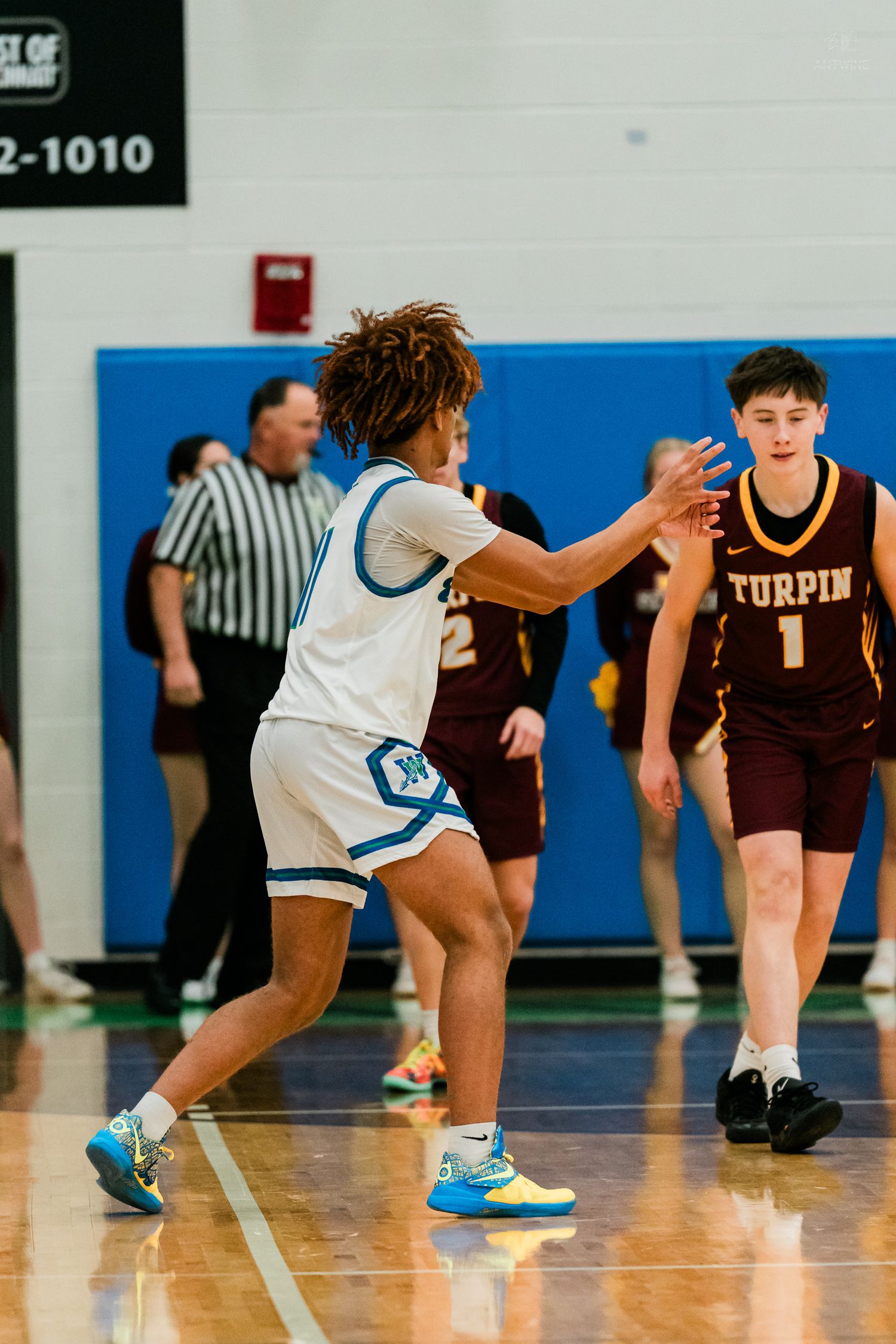 Winton Woods player guards Turpin number 1 during a high school basketball game with a referee in the background.