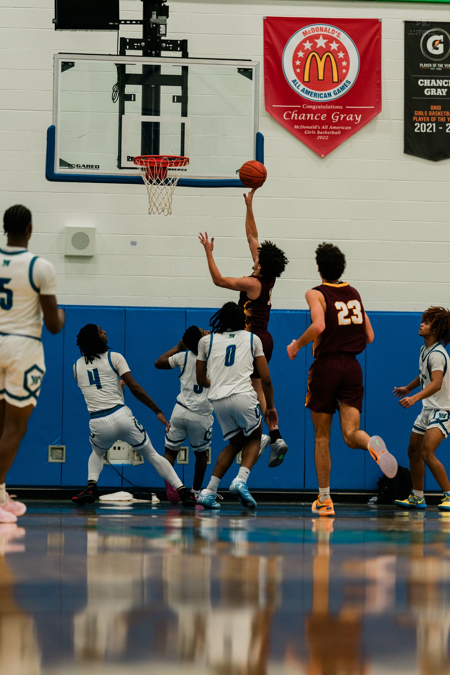 Basketball player attempts a layup near the rim beneath a McDonald's All American banner honoring Chance Gray.