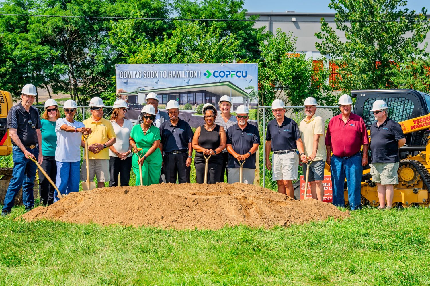 Large group photo at COPFCU Hamilton groundbreaking ceremony with hard hats and golden shovels.