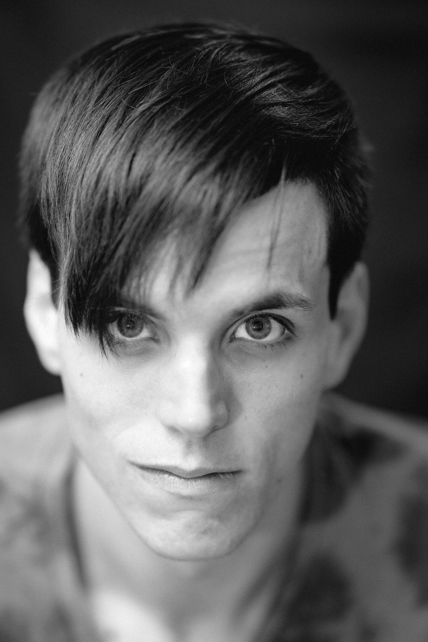 Dramatic black and white close-up portrait of young man with sweeping dark bangs.