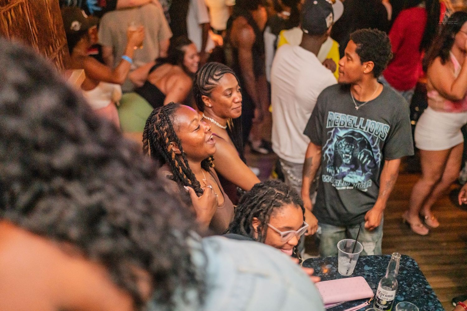 Young women with braided hair socializing and dancing at a lively crowded indoor nightclub party.