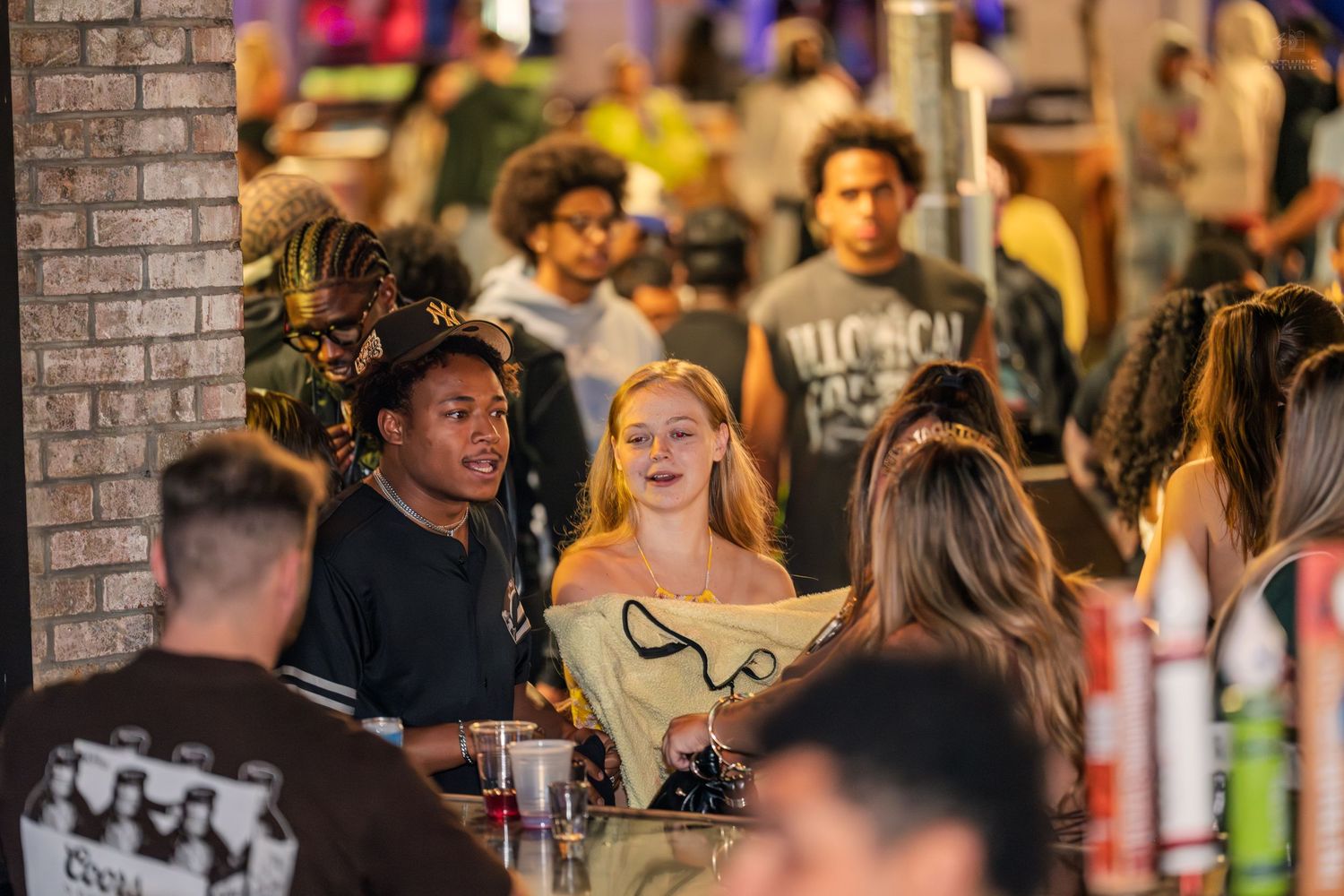Diverse group of young adults socializing around a table at a lively outdoor bar.