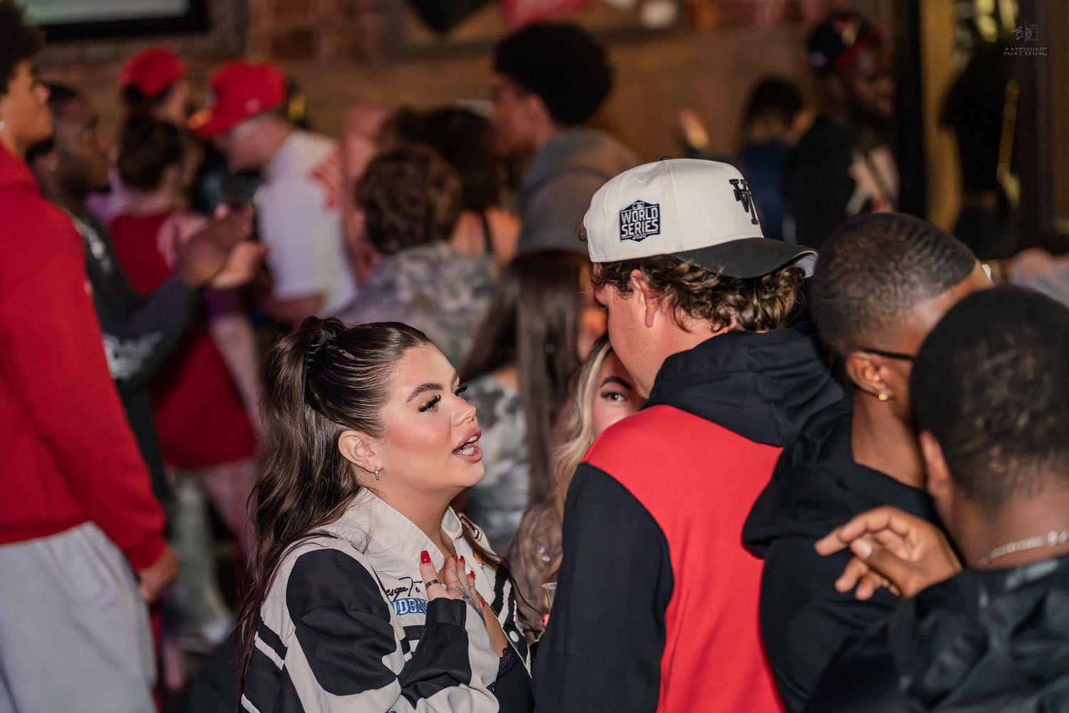 Young woman in racing jacket chatting with friends at an outdoor nighttime event.