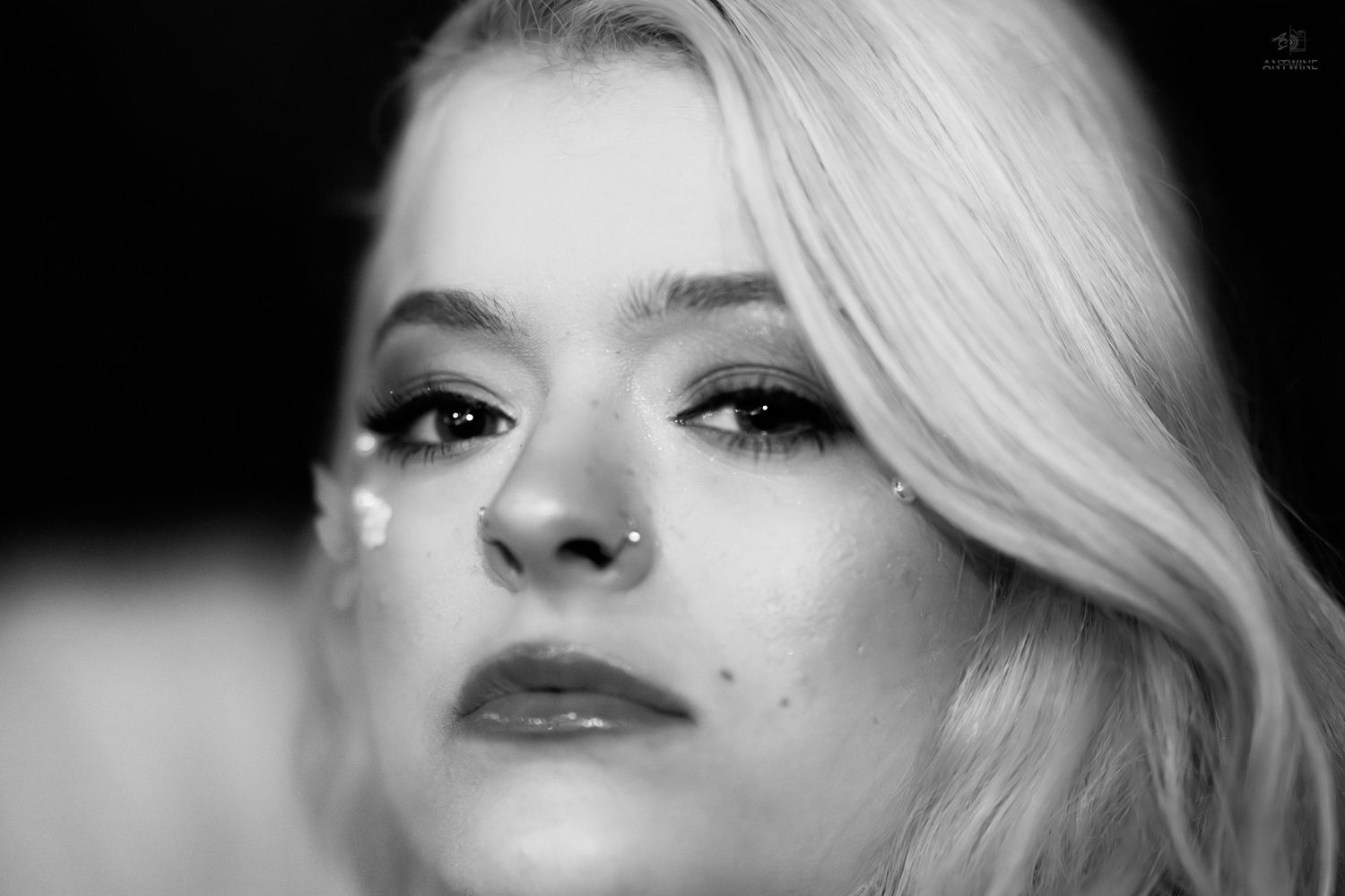 Black and white close-up portrait of blonde woman with glitter and bold eye makeup.