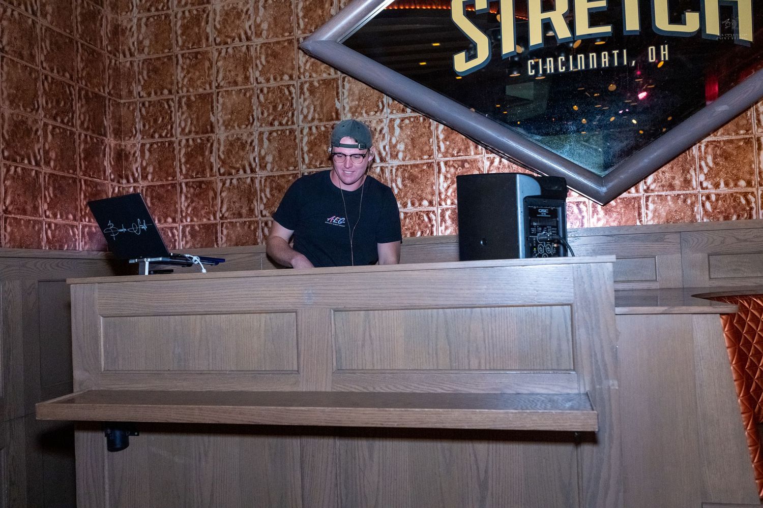DJ standing behind wooden booth at Stretch Cincinnati OH entertainment venue.