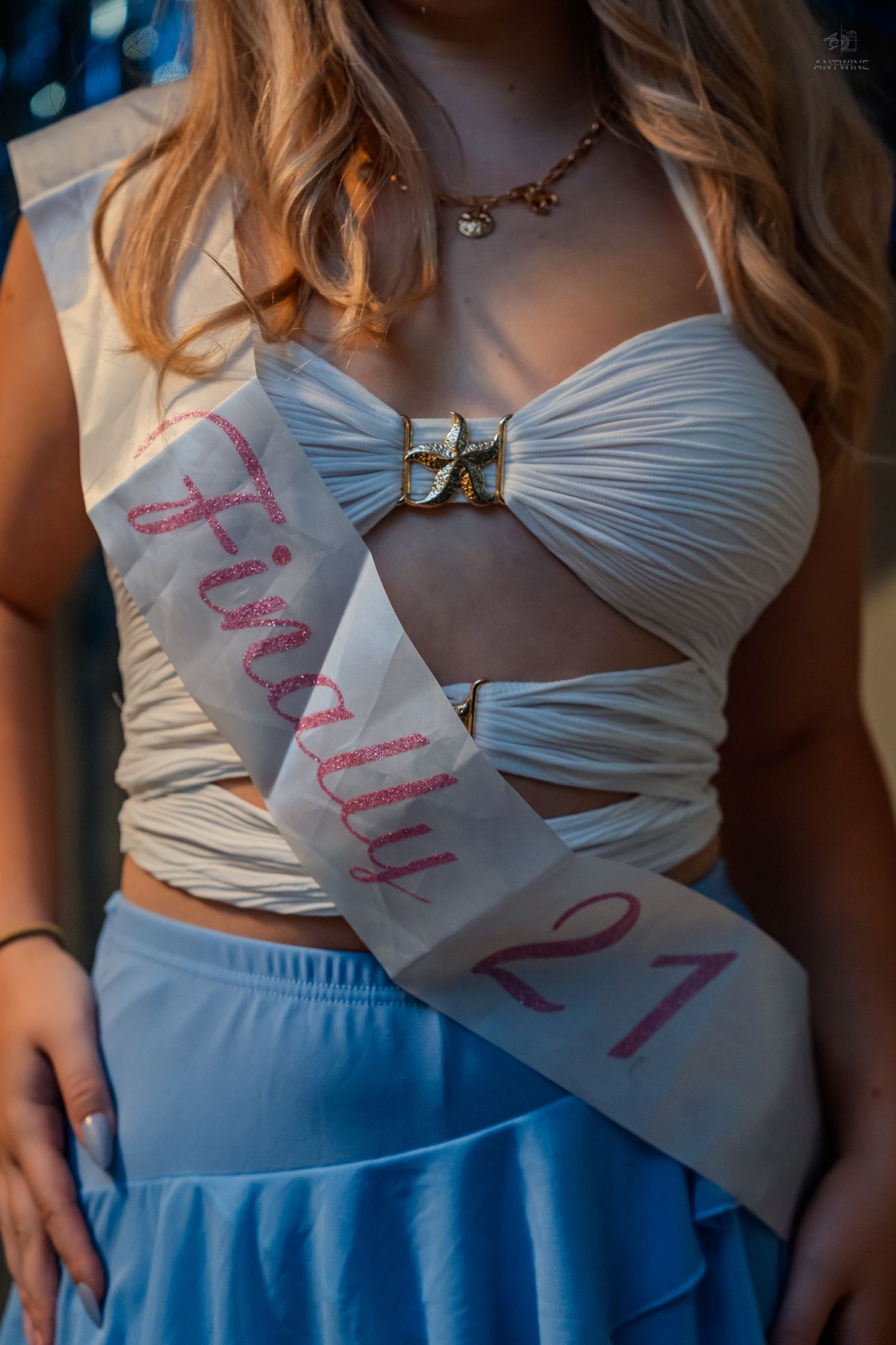 Close-up of birthday girl wearing Finally 21 sash with white crop top and gold necklace.