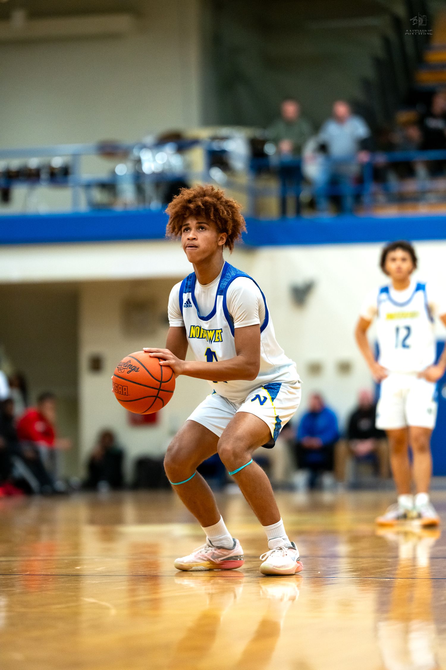 Northwest high school basketball player dribbles ball during game with teammate visible in background.