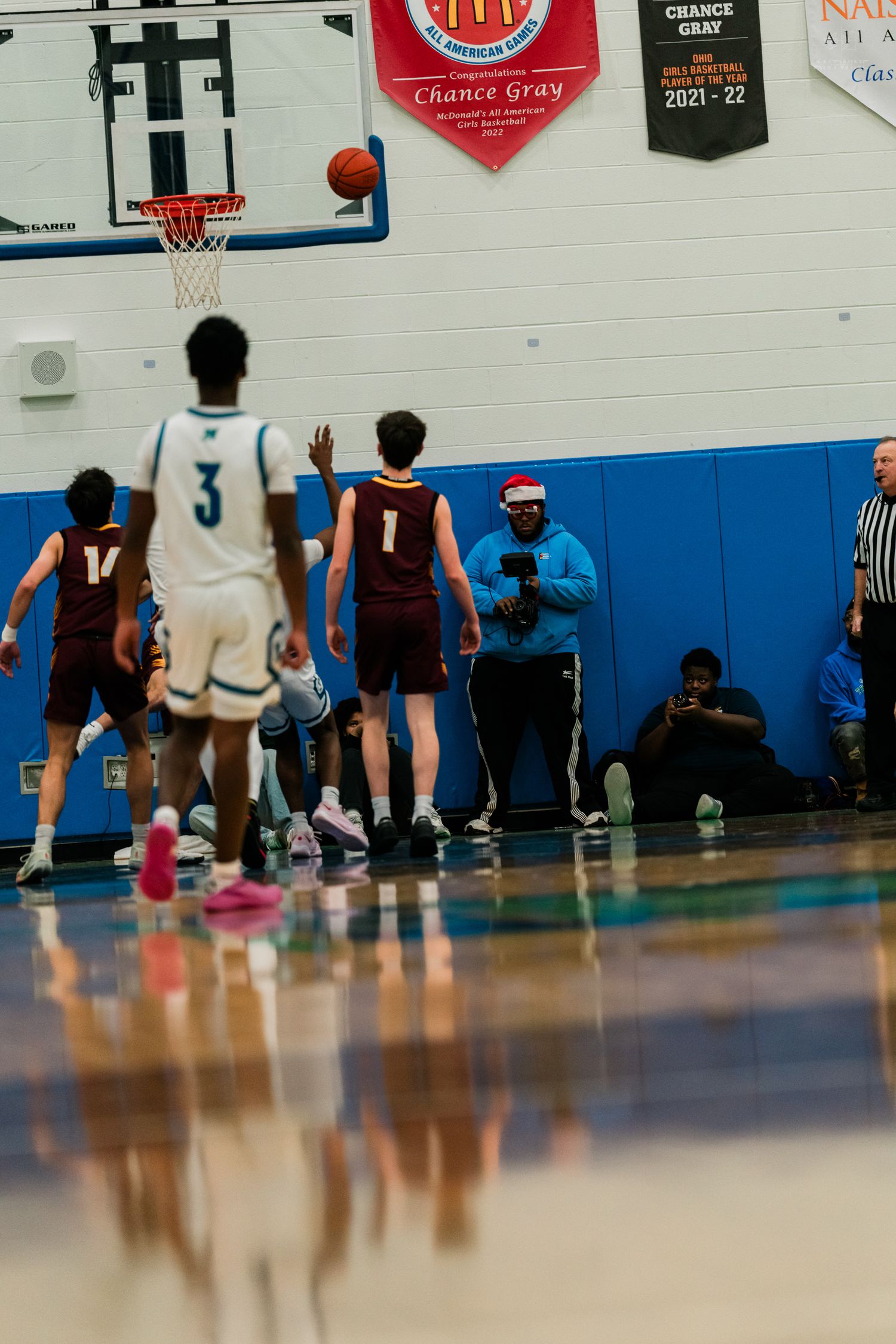 High school basketball game with players in maroon and white uniforms near the hoop as a shot goes up.