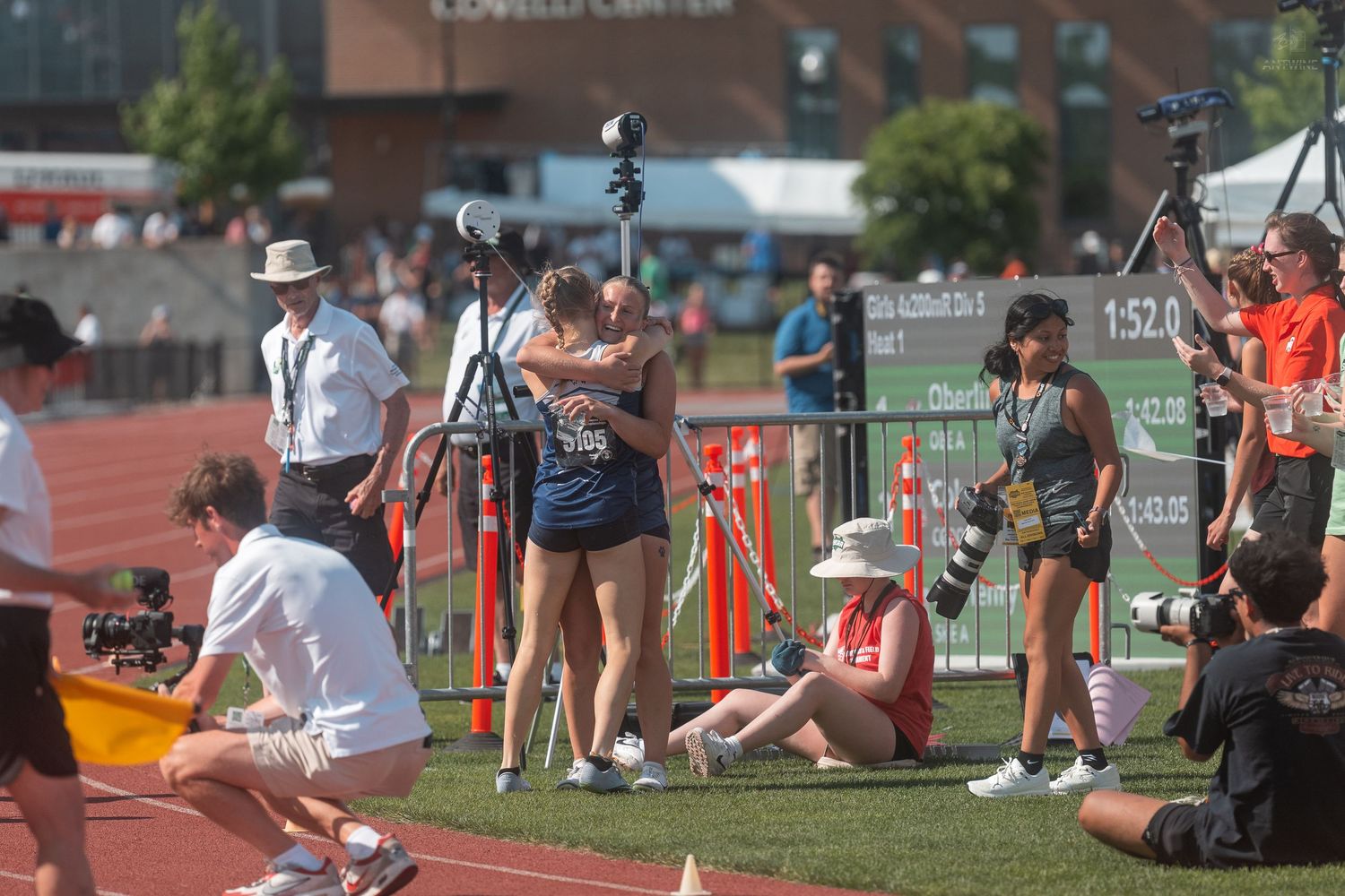 Two athletes embrace at the finish line of a track meet outside the Lovelli Center.