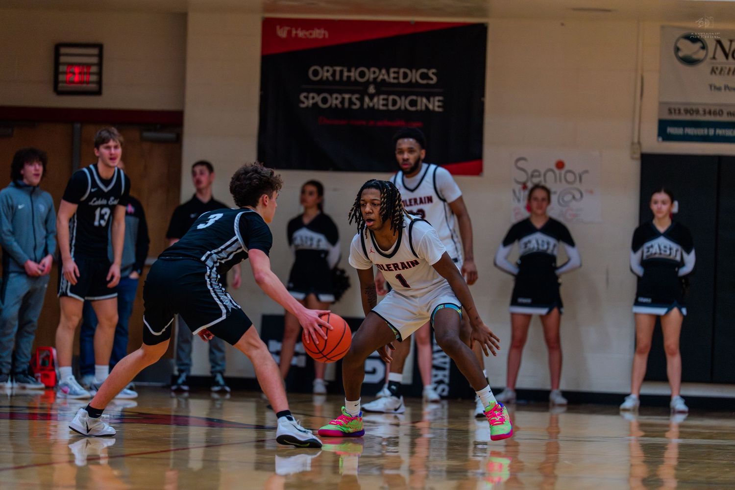 Colerain #1 guards opponent near Orthopaedics and Sports Medicine banner during game.