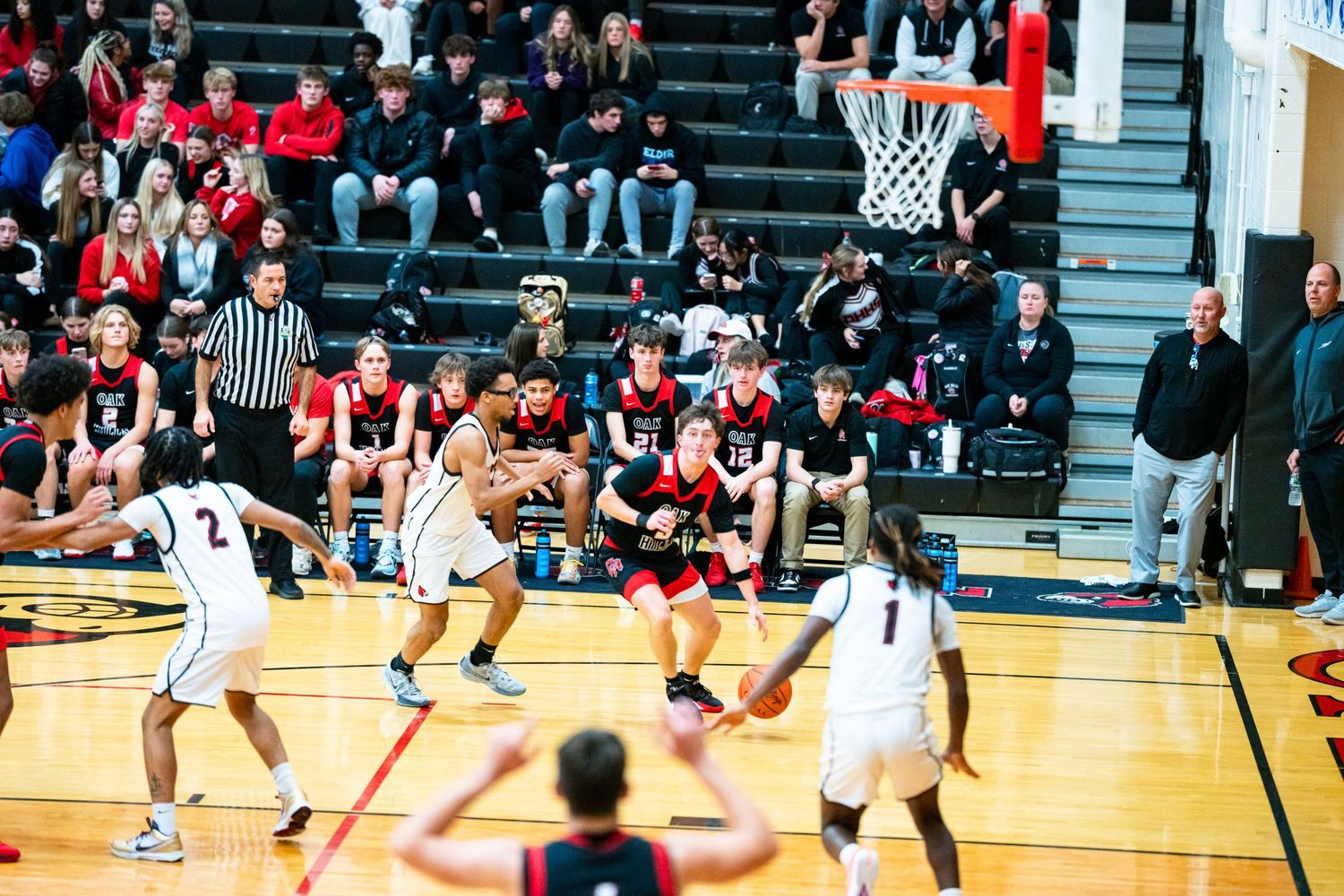 Teams compete in crowded high school basketball game with packed spectator stands.