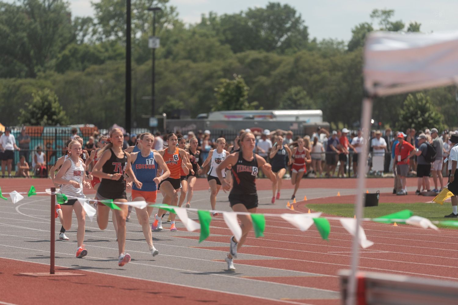 Female runners cross the finish line in a close race at an Ohio State track and field meet.