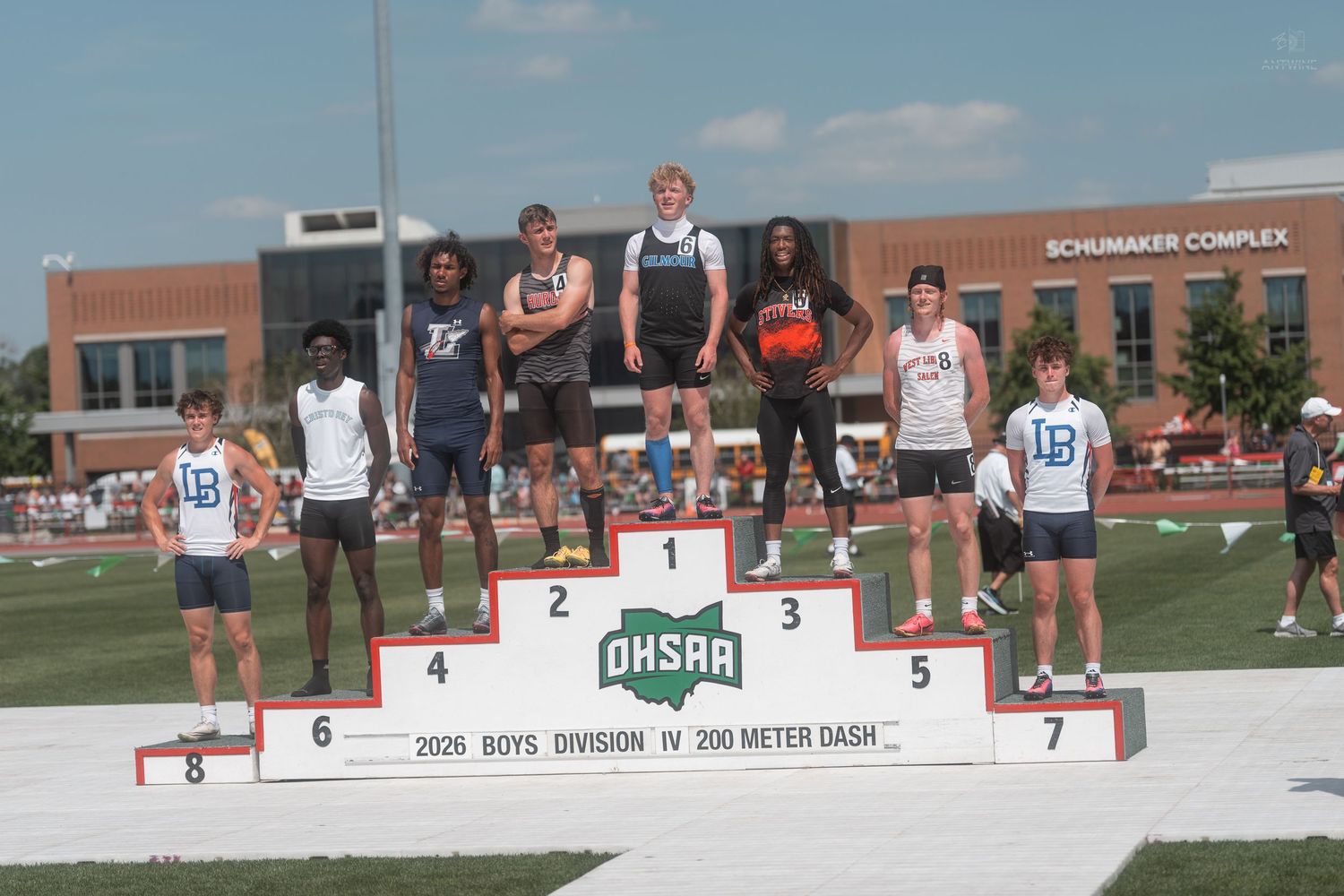 Eight male athletes stand on the OHSAA Boys Division IV 200 Meter Dash awards podium outdoors.