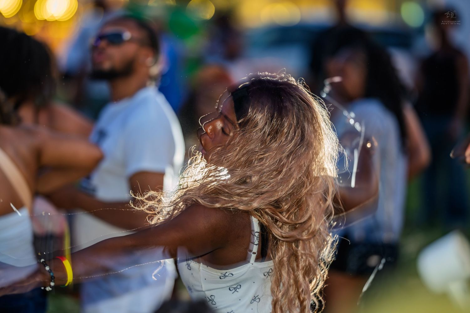 Woman dancing outdoors at Juneteenth festival with long hair flowing in golden evening light.
